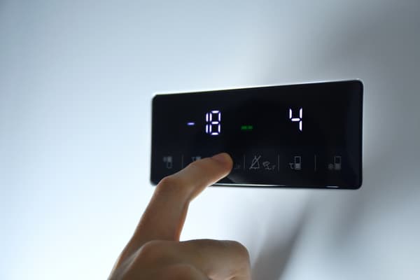 A person selecting temperature settings on a fridge